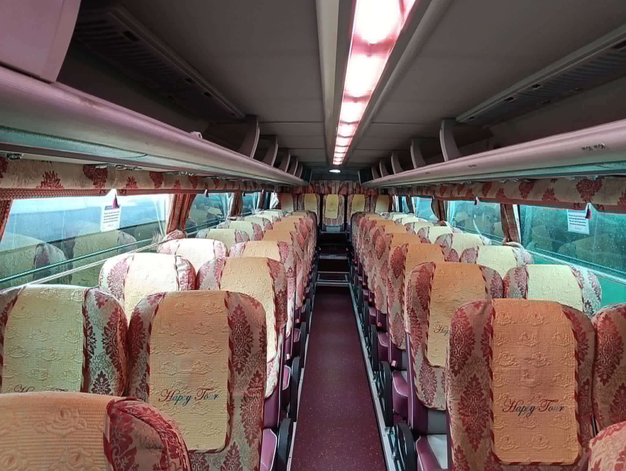 Looking down the aisle of a King's Coach cabin: rows of reclining seats with patterned covers under a lit overhead rack.
