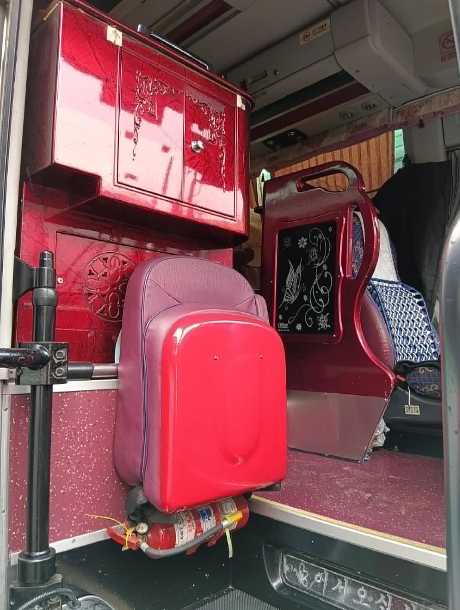 Front entry of the coach: burgundy lacquered console and cabinet, a fold-down guide's seat, and the fire extinguisher by the step.