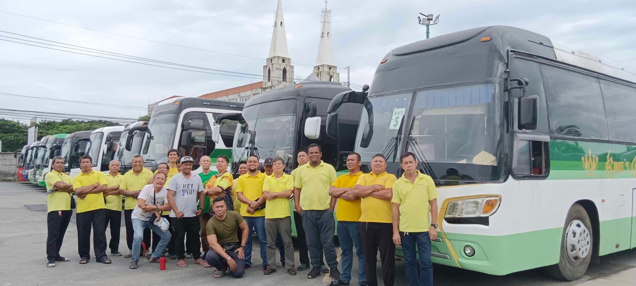 The King's Coach drivers and staff in yellow polo shirts, standing together in front of the fleet lined up at the Parañaque garage.